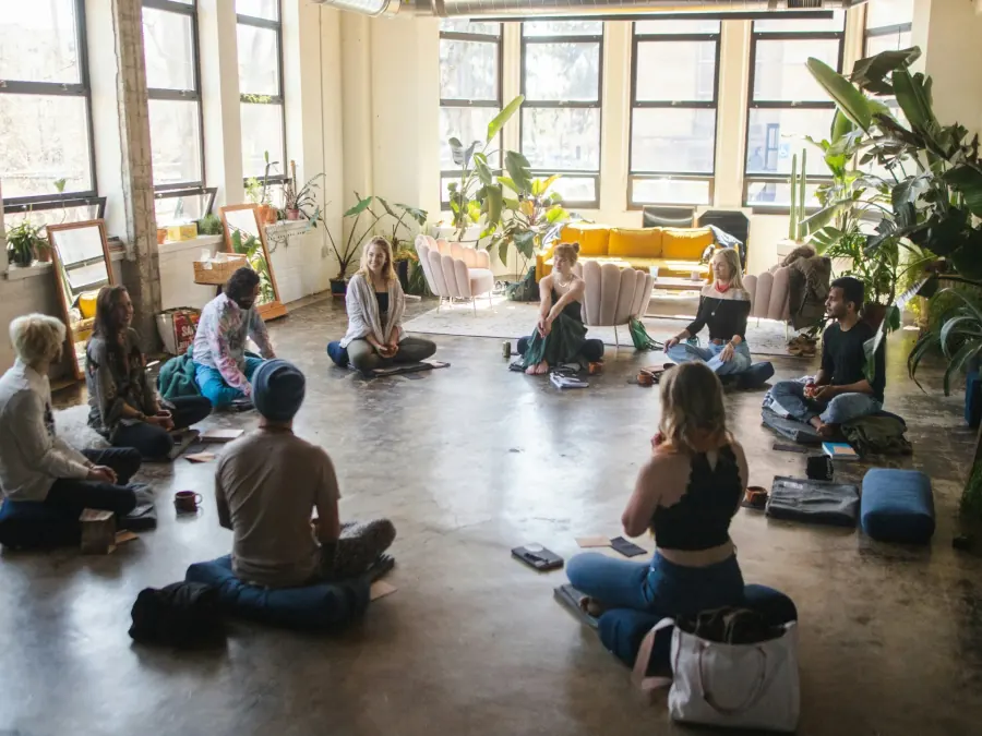 A circle of people meeting in a plant-filled loft.