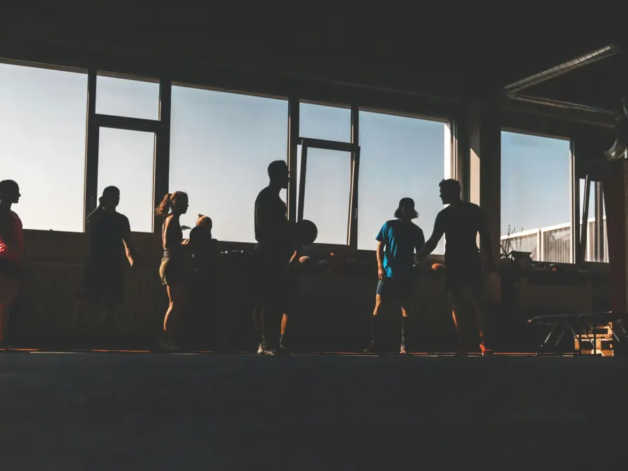 Silhouettes training in a gym at dusk.
